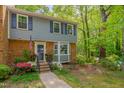 Inviting exterior view showcasing a blue townhouse with brick, blue shutters, flowers, and an American flag at 225 Bay Dr, Cary, NC 27511
