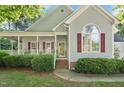Inviting home exterior with a cozy front porch, red shutters, and manicured landscaping at 304 Parkridge Dr, Clayton, NC 27527