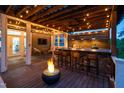 Covered outdoor kitchen with bar seating, a grill, and a cozy fire pit on the deck at 3215 Bellamy Ridge Dr, Apex, NC 27523