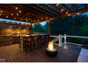 Beautiful outdoor kitchen on a covered deck with a grill, bar, and inviting fire pit at 3215 Bellamy Ridge Dr, Apex, NC 27523