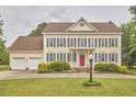 Traditional two-story home featuring a two-car garage, red front door, manicured lawn, and tasteful landscaping at 3809 Victorian Grace Ln, Apex, NC 27539