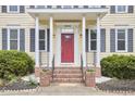 Charming front porch with brick steps, decorative plants, and a vibrant red door at 3809 Victorian Grace Ln, Apex, NC 27539