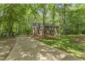 Scenic view of long driveway leading to traditional brick home amid a lush green, wooded landscape at 4041 Brook Cross Dr, Apex, NC 27539