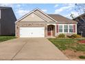Inviting home featuring stone accents, a two-car garage, a well-kept lawn, and a welcoming red front door at 46 S Great White Way, Clayton, NC 27527