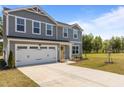 Two-story home with attached two-car garage, vinyl siding, long driveway, and manicured lawn at 473 Lavatera Dr, Wendell, NC 27591