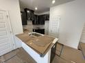 Well-lit kitchen with stainless steel sink, dark cabinets with subway tile backsplash, and a breakfast bar at 505 Eastwood St, Durham, NC 27704