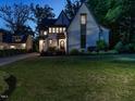 A charming two-story home with white brick, gray trim, and a large, well-maintained front lawn at dusk at 602 Shelley Rd, Raleigh, NC 27609