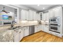 Bright kitchen with white cabinets, granite countertops, stainless steel appliances, and hardwood floors at 716 Streamwood Dr, Holly Springs, NC 27540