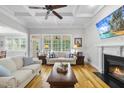 Bright living room features coffered ceilings, hardwood floors, fireplace, and large windows at 716 Streamwood Dr, Holly Springs, NC 27540
