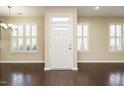 Bright foyer with hardwood floors, white door, and windows with plantation shutters at 7229 Terregles Dr, Raleigh, NC 27617