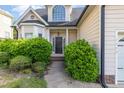 Inviting front entrance with lush landscaping leading to a dark wood door with columned portico at 7940 Milltrace Run, Raleigh, NC 27615