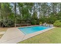 Refreshing backyard pool featuring a waterfall, lounge, and mature trees at 84 N Hadrian Ct, Clayton, NC 27520