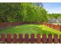 Spacious backyard with a lush green lawn, surrounded by a wooden fence and mature trees at 8401 Hobhouse Cir, Raleigh, NC 27615