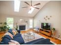 Bright living room with a fireplace, skylights, ceiling fan and hardwood floors with large blue sectional at 101 Lakeshore Dr. Dr, Durham, NC 27713