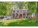 Eye-level view of a home with mature trees, large lawn, and covered porch with a red front door at 1107 Daleland Dr, Raleigh, NC 27612
