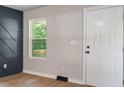 Bright entryway featuring wood-look floors, a modern accent wall, and a classic white front door at 1513 Fairfax Rd, Durham, NC 27701