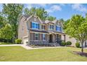 Attractive two-story home with a two car garage, landscaped lawn, and covered front porch with stone accents at 1557 Tice Hurst Ln, Apex, NC 27502