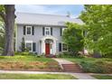 Beautiful gray two-story home with a red front door, black shutters and brick walkway at 1603 Hermitage Ct, Durham, NC 27707