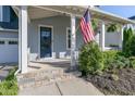 Inviting front porch with stone steps, white columns, American flag and manicured landscaping at 208 Vervain Way, Holly Springs, NC 27540
