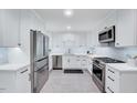 Modern kitchen featuring stainless steel appliances, white cabinets, and gray tile flooring at 212 Ronaldsby Dr, Cary, NC 27511