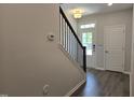 Welcoming entryway with hardwood floors and a staircase featuring black metal railings and white risers at 3020 Freewinds Way # 47, Cary, NC 27519