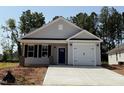 Charming single-story home featuring a blue door, garage and a well-lit porch at 31 Goldenrod Loop, Clayton, NC 27520