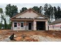 An unfinished exterior of a one-story home with an attached garage under construction with tree line background at 31 Goldenrod Loop, Clayton, NC 27520
