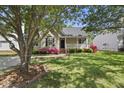 Inviting single-story home features a cozy front porch surrounded by lush greenery and vibrant azalea bushes at 3519 Streams Of Fields Dr, Raleigh, NC 27604