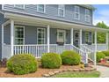 Inviting front porch with white railings, flower boxes, and manicured shrubs at a charming home at 3805 Euliss Rd, Burlington, NC 27215