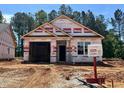 Exterior view of a house under construction with a two-car garage, awaiting its final touches and landscaping at 41 Goldenrod Loop, Clayton, NC 27520