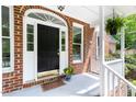 Inviting front porch with a dark door, white trim, brick accents, and a hanging fern for added charm at 4215 Cobscook Dr, Durham, NC 27707