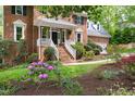 Landscaped front yard showcasing a classic brick home with flowering plants, lush greenery, and a welcoming entrance at 4215 Cobscook Dr, Durham, NC 27707
