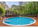 Inviting pool area with a wooden deck and lounge chairs, surrounded by mature trees for privacy at 4405 New Brighton Dr, Apex, NC 27539