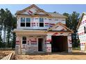 Under-construction two-story home featuring a modern design, visible framing, and protective housewrap at 49 Goldenrod Loop, Clayton, NC 27520