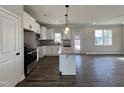 Modern kitchen featuring white cabinets, granite countertops, stainless steel appliances, and hardwood floors at 49 Goldenrod Loop, Clayton, NC 27520