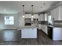 Modern kitchen featuring white cabinets, granite countertops, stainless steel appliances, and hardwood floors at 49 Goldenrod Loop, Clayton, NC 27520
