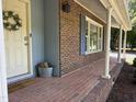 Inviting front porch with brick flooring, white columns, and a decorative wreath at 5026 Gatewood Drive Dr, Durham, NC 27712