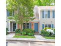 Charming townhome exterior featuring gray siding, brick accents, blue shutters, and mature landscaping at 53 Forest Oaks Dr, Durham, NC 27705