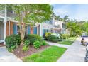 Exterior view of townhomes showcasing well-maintained landscaping, brick accents, and blue shutters at 53 Forest Oaks Dr, Durham, NC 27705