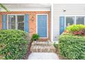 Inviting front door with blue shutters, a charming brick facade, and lush landscaping at 53 Forest Oaks Dr, Durham, NC 27705