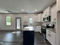 Well-lit kitchen with granite counters, stainless appliances, an island, and gray hardwood floors at 57 Goldenrod Loop, Clayton, NC 27520