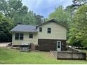 Two-story home with yellow siding, brick foundation, dark roof, rear deck, and a grass lawn at 7412 Barberry Ct, Raleigh, NC 27615