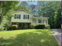 Two-story home with yellow siding, brick foundation, covered front porch, and manicured lawn surrounded by lush greenery at 7412 Barberry Ct, Raleigh, NC 27615