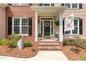 Inviting front porch with brick steps, decorative wreath, and a 'Welcome' flag at 1003 Fairfax Woods Dr, Apex, NC 27502