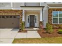 Elegant front entryway featuring a stone facade, covered porch, and stylish entry door at 1005 Whispering Creek Ct, Knightdale, NC 27545
