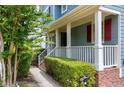 Close-up of a charming covered front porch with white railings and manicured landscaping at 103 Trent Woods Way, Cary, NC 27519