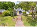 Charming exterior view of a single-story home with a yellow front door, brick walkway, mature landscaping, and a quaint front porch at 107 E Hammond St, Durham, NC 27704
