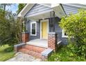 Close-up of a home's entrance, featuring a yellow door, brick-lined porch, and decorative black iron railings at 107 E Hammond St, Durham, NC 27704