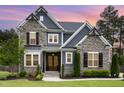 Charming two-story home at sunset featuring a stone facade, gray siding, wood accents, and a manicured front yard at 1112 Valley Rose Way, Durham, NC 27712