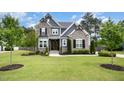 Beautiful two-story home with stone and gray siding, complemented by a lush green lawn and manicured landscaping at 1112 Valley Rose Way, Durham, NC 27712